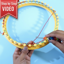 Load image into Gallery viewer, Loom Knit Mock Mesh Stitch Pattern. A close-up of a yellow circular knitting loom with colorful yarn wrapped around it, held by hands against a light blue background.
